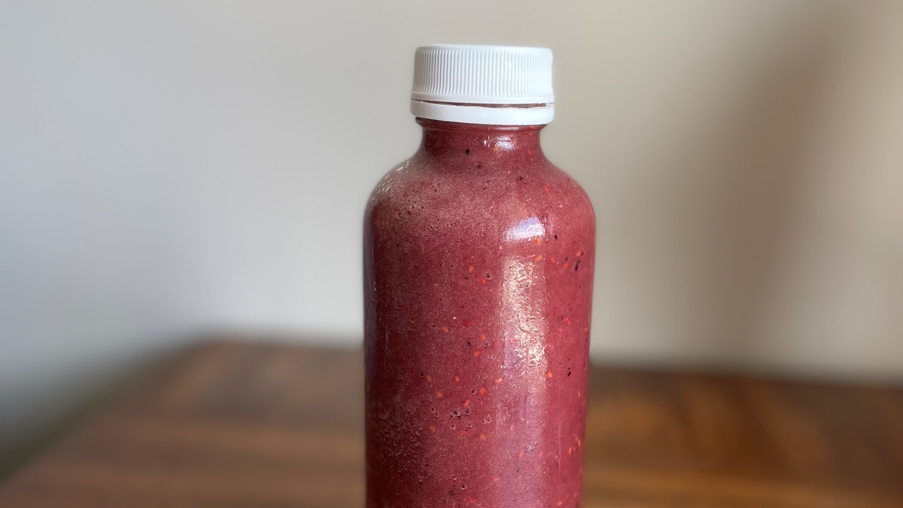 A photo of berry juice in a glass bottle. 