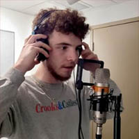 Lucas Dimattia (LLD) wearing headphones, standing in front of a microphone.